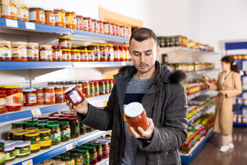 Adult man buyer in casual clothes chooses lecho in store