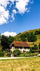 A charming, traditional country house nestled within a picturesque valley, bathed in the warm sunlight of a beautiful summer day.