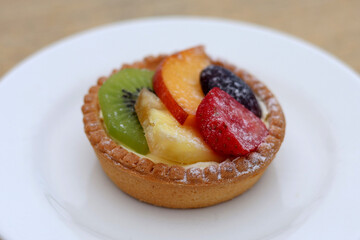 Delicious fruit tart with custard cream, topped with fresh fruits, lightly dusted with powdered sugar. Perfect for cafés, bakeries, and food catalogs.