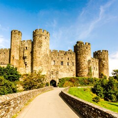 A majestic medieval stone castle stands proudly against a vibrant, clear sky.