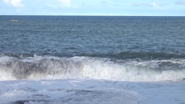 A black beach made of sea-rolled particles of pyroclastic material on a volcanic island. Bunaken, Sulawesi Sea. Indonesia