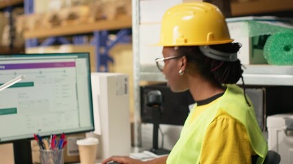 African american female verifying the shipment details on awb labels, using package tracking software system with accurate order status. Monitoring import export operations in depot. Camera B.