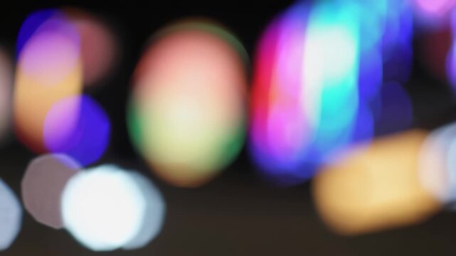 This video showcases vibrant, colorful bokeh lights softly glowing and blending in the darkness. The mesmerizing out-of-focus patterns evoke a dreamy, abstract city nightlife and create a visually enc