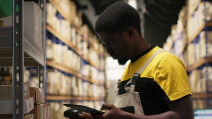 African american man using scanner to register barcodes tags in inventory, solving logistics operations in industrial warehouse. Worker checking shipping labels near storage racks. Camera B.