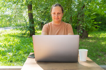 Mature caucasian woman working on laptop outdoors in park