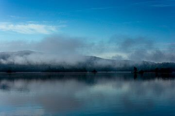 Misty morning over a calm lake,.  Peaceful and tranquil nature scene in shades of blue,  blue  hour