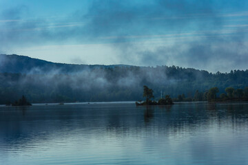 Misty morning over a calm lake,.  Peaceful and tranquil nature scene in shades of blue,  blue  hour