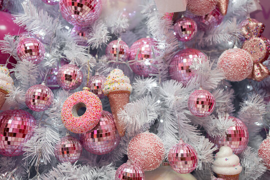 Closeup of beautiful white Christmas tree decorated with pink shiny balls and ice creams. Festive holiday concept, showcasing a unique and playful decoration