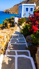 A sun-drenched coastal walkway leads to a vibrant blue house, surrounded by colorful bougainvillea.
