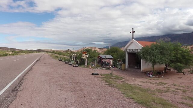 Panoramic view of El Degolladito Sanctuary in Catamarca, Argentina. The road in the desert and the high clouds create an atmosphere of mystical and unsettling solitude