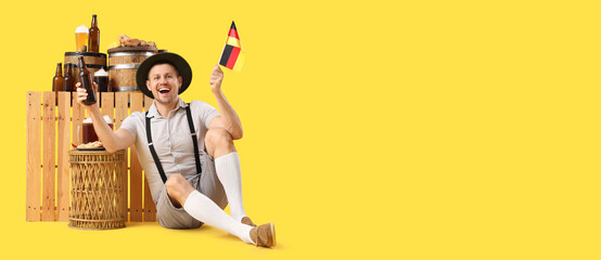 Mature happy man in traditional clothes with bottles of beer, snacks and German flag on table...