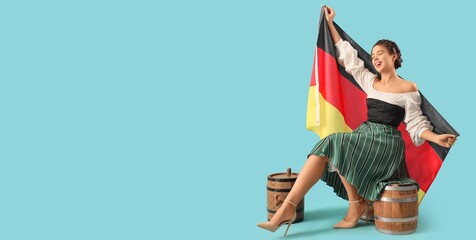 Happy young woman with German flag and barrels of beer on blue background with space for text....