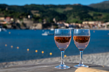Glasses of rose Collioure AOC wine in sunlights with view on old town Collioure, colorful houses, church, castle and beaches, Occitanie, France, tourists destination