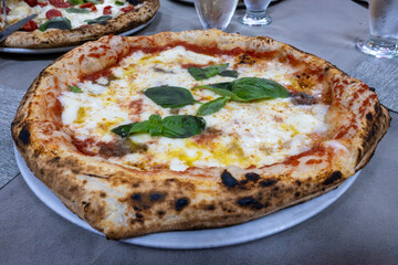 Eating of fresh baked Naples pizza dish in italian pizzeria restaurant, close up