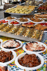 Delicious fresh cooked street food on daily food market in Palermo, Sicily, travel destination, food tourism Italy, variety of raw, roasted, grilled fish, seafood, meat, vegetables snacks or dshes