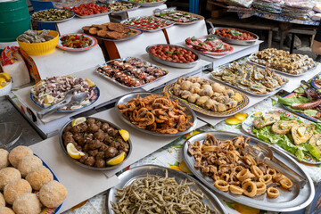 Delicious fresh cooked street food on daily food market in Palermo, Sicily, travel destination, food tourism Italy, variety of raw, roasted, grilled fish, seafood, calamari, sea urchins
