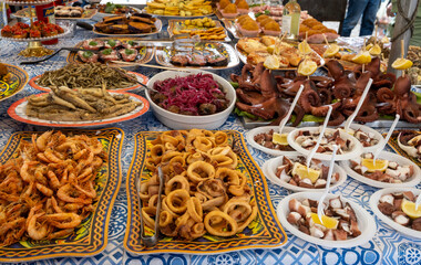 Delicious fresh cooked street food on daily food market in Palermo, Sicily, travel destination, food tourism Italy, variety of raw, roasted, grilled fish, seafood, calamari, sea urchins