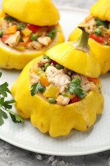 Tasty stuffed pattypan squashes on grey textured table, closeup