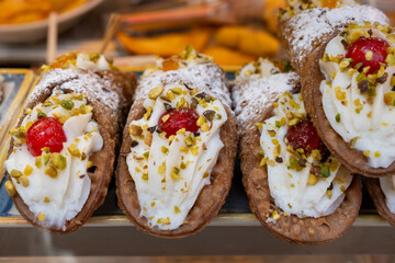 Homemade sweet pastry cannolo sfoglie filled with almond, pistachio, lemon, vanilla, chocolate cream on food market in Palermo, Sicily, Italy