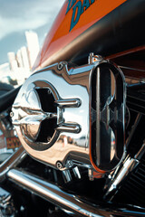 Close-up of the chrome air filter of a motorcycle, with part of the orange fuel tank visible in the background.