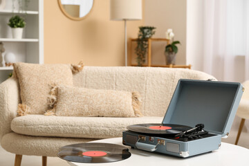 Record player with disks on coffee table in room