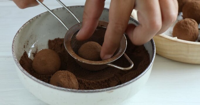 Woman making homemade candies at white wooden table, closeup