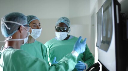 serious diverse surgeons with face masks inspecting xray in operating room in slow motion 4k video - Powered by Adobe