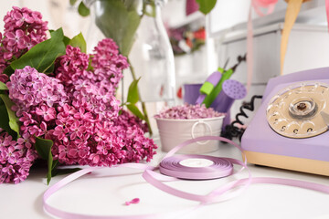 Lilacs with ribbon and retro phone on table in florist studio