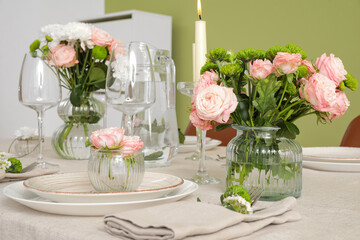 Beautiful table setting with flowers and candles near green wall in dining room
