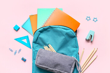 School backpack with different stationery supplies on pink background