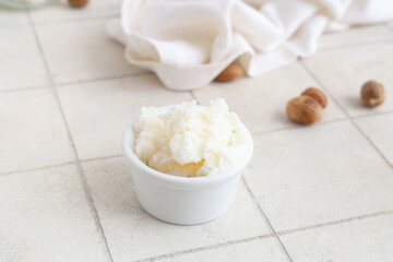 Bowl of shea butter on light tile background