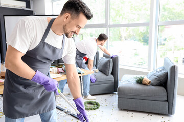 Male janitor mopping in office after New Year party