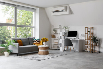Interior of living room with grey sofa, modern workspace and sunflowers on coffee table