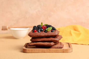Wooden board of sweet chocolate Belgian waffles with fresh berries and mint on yellow background