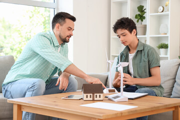 Teenage boy and his father with wind turbine models on table at home