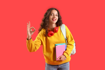 Female student with copybooks showing OK on red background