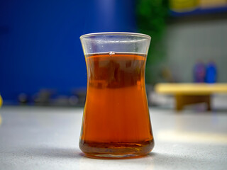 A traditional Turkish tea glass filled with hot black tea is sitting on a modern kitchen counter creating a contrast between old customs and contemporary life