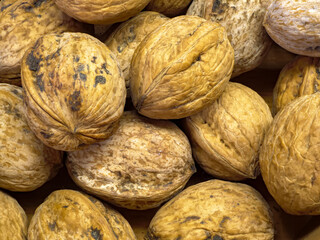 A macro photograph of whole walnuts stacked together highlighting the intricate lines and unique marbled patterns on each shell making a great natural texture