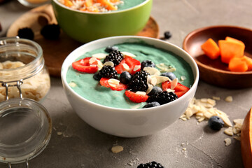 Bowl of tasty spirulina smoothie on grey grunge background, closeup