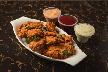 Fried chicken on a plate with sauces around it.