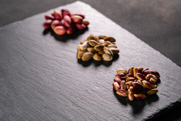 Raw pistachios on granite surface. Fresh pistachio Nuts on grey stone. Pile of pistachios on grey granite. Natural pistachios on stone texture.