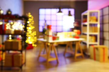 Blurred view of post office with gift boxes, laptop, shelving units and Christmas decorations at evening