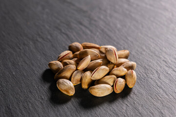 Raw pistachios on granite surface. Fresh pistachio Nuts on grey stone. Pile of pistachios on grey granite. Natural pistachios on stone texture.