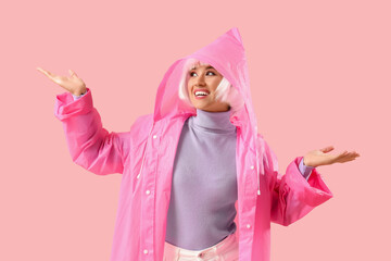 Beautiful young happy woman in white wig and raincoat on pink background