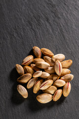 Raw pistachios on granite surface. Fresh pistachio Nuts on grey stone. Pile of pistachios on grey granite. Natural pistachios on stone texture.