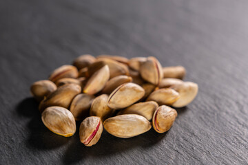 Raw pistachios on granite surface. Fresh pistachio Nuts on grey stone. Pile of pistachios on grey granite. Natural pistachios on stone texture.