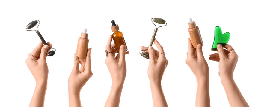 Many female hands with bottles of cosmetic products, facial massage tool and guasha isolated on white background