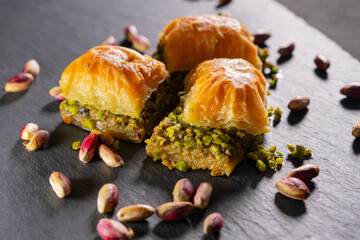 Traditional pistachio baklava on granite. Close-up of pistachio baklava on granite background. Turkish dessert baklava with pistachios. Pistachio baklava on stone surface.