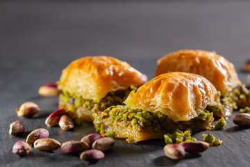 Traditional pistachio baklava on granite. Close-up of pistachio baklava on granite background. Turkish dessert baklava with pistachios. Pistachio baklava on stone surface.
