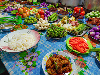 Various vegetable and meat curry, Shrimp Paste Dip, various chili pastes on a table in a restaurant. cauliflower, radish, Cabbage, okra, carrot, cucumber, mango, purple eggplant, winged beans